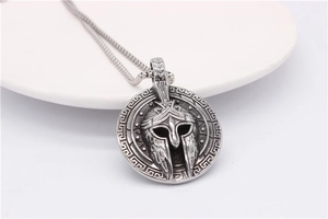 Close-up of vintage steel Spartan helmet pendant with Greek key pattern border