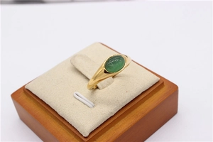 Dettaglio di un anello a sigillo dorato con gemma verde a occhio di gatto ovale