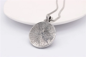 Macro view of round silver pendant with radial texture and steel box chain