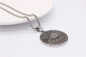 Macro shot of silver titanium steel zodiac compass pendant with intricate ethnic carvings
