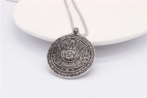 Detailed macro view of vintage Aztec calendar pendant in silver-tone steel finish
