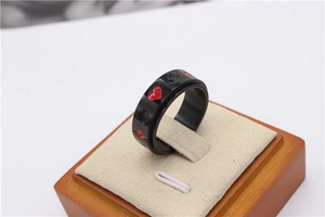 Détail macro de la bague rotative en titane noir avec motifs de cœur et pique rouges