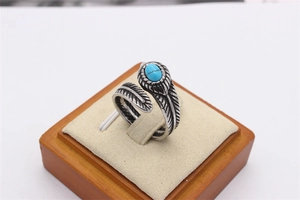Vue détaillée d'une bague plume rétro en acier avec pierre turquoise sur support