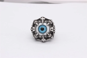 Detail of gothic silver skull ring featuring a blue evil eye stone and metal claw carving
