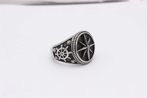 Macro detail of nautical ring featuring embossed compass star and helm on oxidized steel