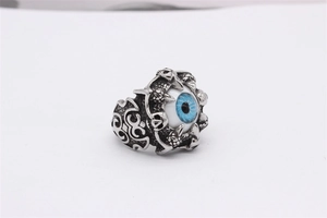 Macro shot of punk skull ring featuring a blue evil eye held by silver steel claws