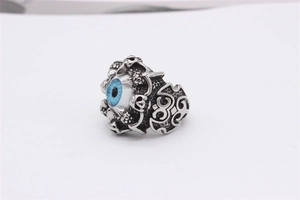 Macro shot of vintage steel ring featuring a blue evil eye and gothic claw details