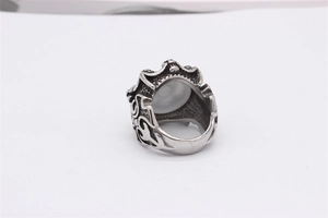 Detail of vintage silver skull ring featuring intricate carvings and a white opal stone