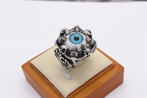 Detail view of gothic skull ring with blue evil eye stone and silver claw setting