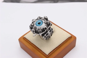 Macro shot of Gothic skull engravings and deep blue evil eye detail on men's steel ring