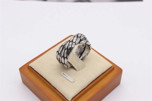 Macro detail of retro X-cross ring showing textured silver leaf patterns and vintage finish
