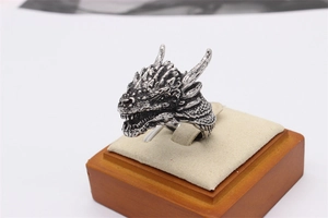 Macro shot of retro dragon head ring in oxidized silver finish on a wooden stand