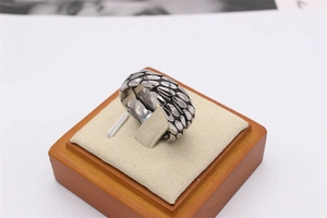 Macro detail of retro wide crisscross ring with oxidized silver scales and eagle feather texture
