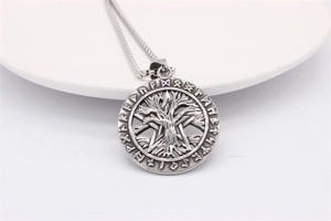 Macro view of vintage silver Tree of Life pendant with Nordic runes on a beaded chain