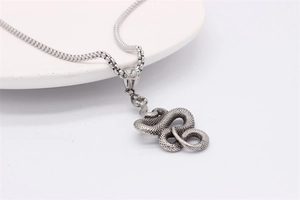 Macro detail of retro silver snake pendant with textured scales on a steel box chain