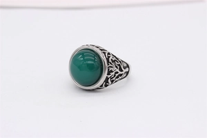 Close-up of vintage tree texture and green gemstone on a polished steel signet ring