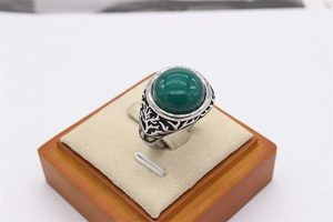 Macro detail of retro tree of life ring with large green gemstone and silver engravings