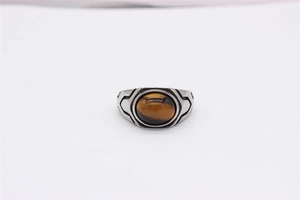 Close-up of retro men's ring with oval tiger eye stone and vintage geometric metal patterns