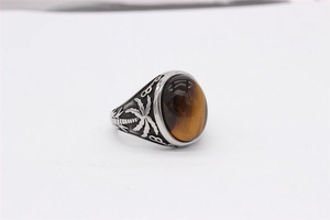Gros plan sur la bague vintage en acier titane avec œil de tigre ovale et motif palmier