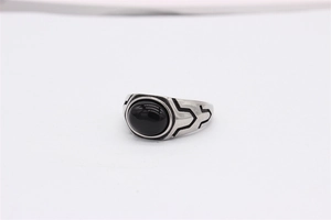 Macro detail of retro steel ring featuring a black oval gemstone and engraved geometric lines