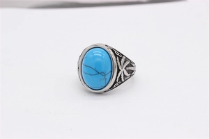 Détail macro de la pierre turquoise ovale et gravure de palmier sur bague en acier rétro
