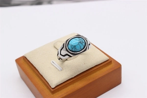 Macro shot of retro men's steel ring with oval turquoise stone on beige suede stand