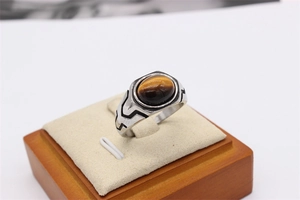 Macro detail of men's stainless steel ring featuring a tiger eye stone and geometric etching