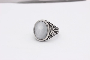 Gros plan d'une pierre blanche ovale et gravures de palmier sur bague en argent