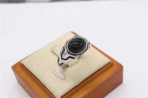 Macro detail of retro men's steel ring featuring black oval stone and geometric carving
