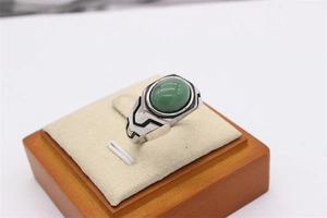 Macro shot of vintage titanium steel ring featuring an oval green gemstone and geometric patterns