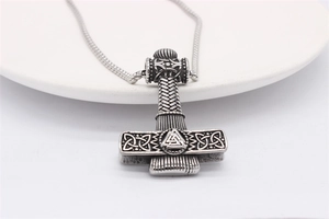 Detailed view of Viking Mjölnir pendant with Celtic knots on a white ceramic plate
