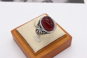 Détail macro d'une bague vintage en acier inoxydable avec pierre ovale rouge et palmier