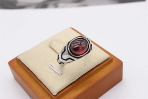 Macro detail of retro steel ring featuring a large oval red gemstone and geometric patterns