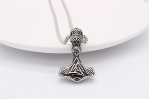 Macro shot of Viking Mjolnir pendant with Valknut symbol and vintage steel texture