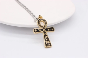 Détail du pendentif croix Ankh égyptienne rétro avec hiéroglyphes noirs sur une assiette blanche