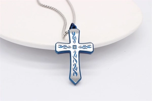 Détail macro du pendentif croix avec motifs tribaux bleus et incrustation de zircon