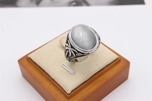 Vue macro d'une bague rétro avec pierre grise ovale et motifs de palmiers ciselés