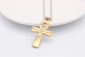 Détail du pendentif croix Ankh en or brossé sur un collier à chaîne serpent argentée