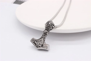 Macro view of vintage silver Viking Mjolnir pendant with Valknut symbol and snake chain