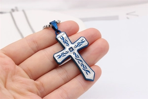 Détail du collier croix bicolore argent et bleu avec motifs de flammes et diamant