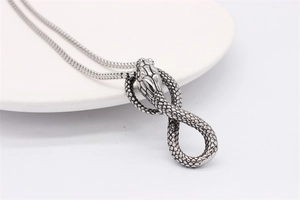 Macro shot of retro cobra snake pendant in vintage silver finish on white background