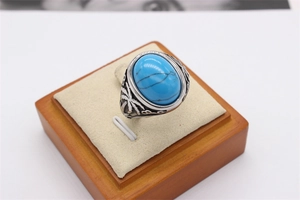 Détail d'une bague rétro avec turquoise ovale et relief de palmier sur acier argenté