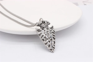 Close-up of vintage silver arrowhead pendant with textured finish on a sleek snake chain