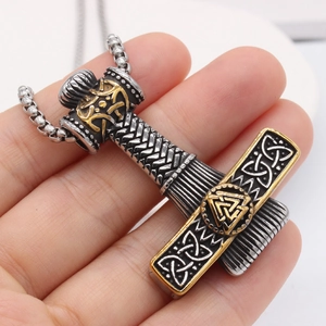 Viking Thor's Hammer Mjolnir necklace in antique steel and gold finish held by hand