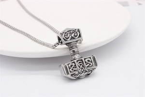 Gros plan du pendentif Mjölnir viking montrant des motifs de nœuds et une texture acier antique