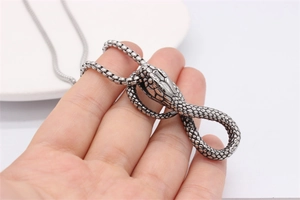 Macro detail of retro cobra snake pendant showing realistic scale texture and box chain