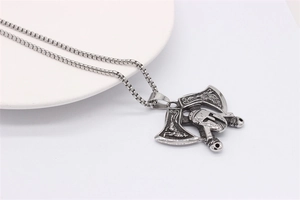 Detail of vintage silver Viking axe pendant necklace with intricate wolf and eagle engravings