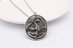Macro detail of vintage stainless steel dragon pendant with antique relief and Cuban chain