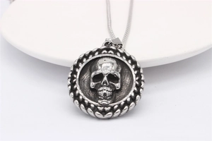 Macro shot of silver skull pendant with braided edge on a white ceramic plate