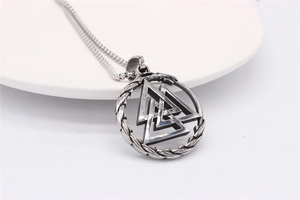 Macro view of vintage silver Viking Valknut pendant with box chain on white ceramic stand